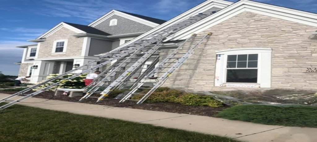 Wisconsin roofing crew tearing off old shingles with a posted building permit on the job site