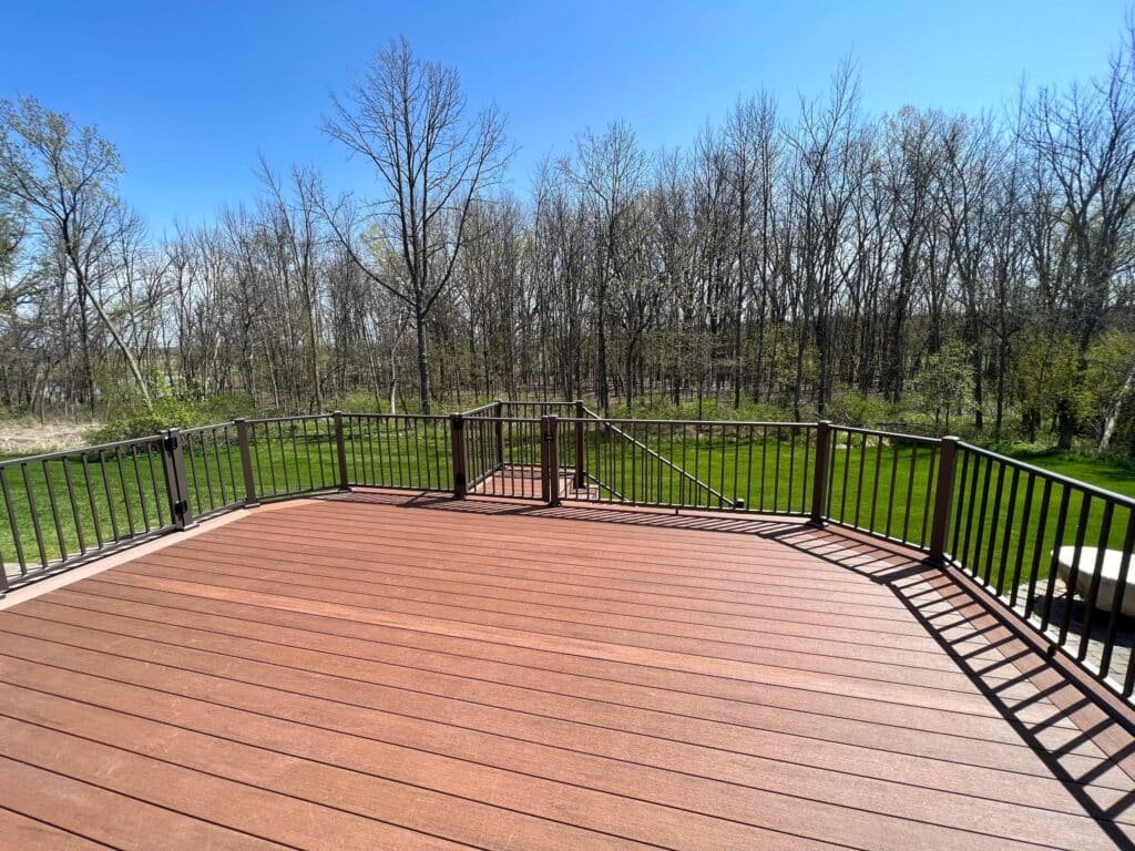 Composite deck with black aluminum railing overlooking a wooded backyard