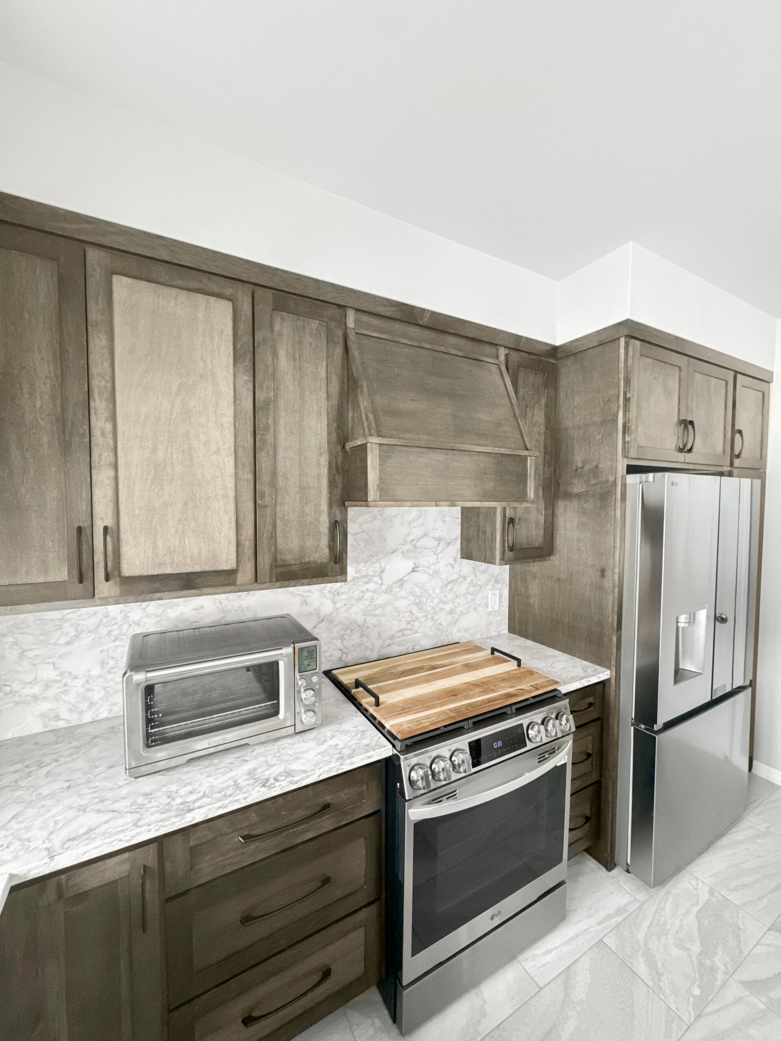 Mid-range kitchen remodel in Wisconsin featuring stained wood cabinetry, marble-look quartz countertops, custom range hood, and stainless steel appliances