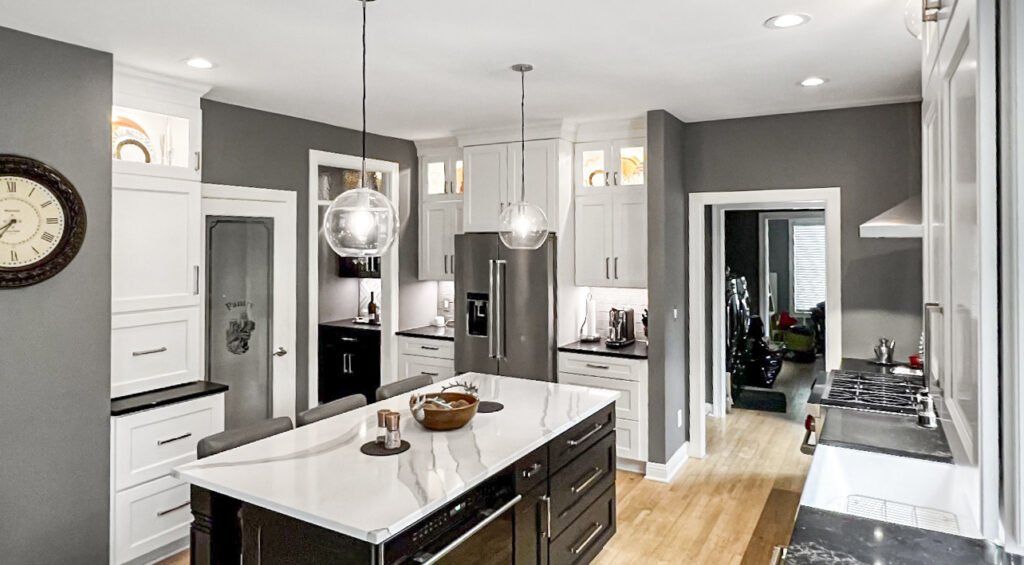 Transitional kitchen with white cabinets, a dark island and pendant lighting