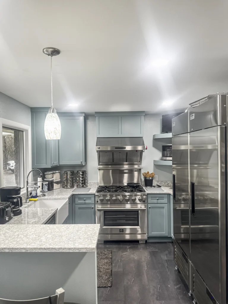 Remodeled kitchen with blue-gray shaker cabinets, a stainless range hood and a professional gas range