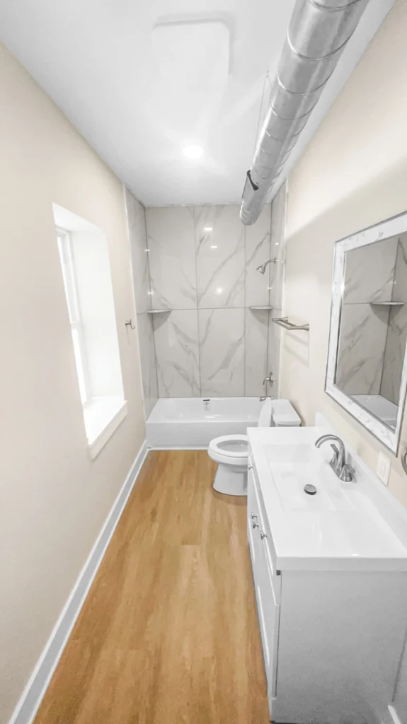 Curbless walk-in tile shower with matte black grab bars and a fold-down bench in a Waukesha County bathroom