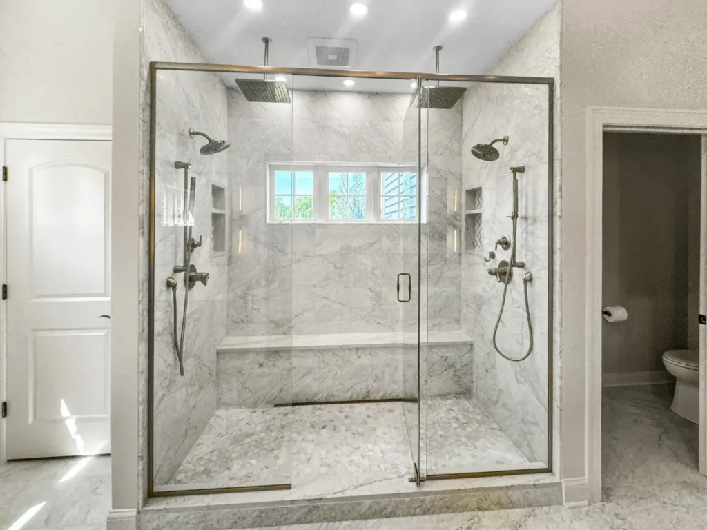 Luxury bathroom remodel with a double walk-in shower, marble-look tile and a glass enclosure