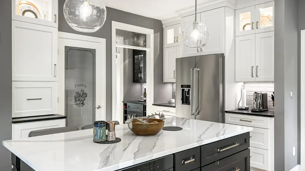 Remodeled kitchen with white perimeter cabinets, a dark island and marble-look quartz countertops